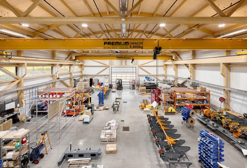 Workshop floor with yellow overhead crane and exposed timber roof trusses above machinery