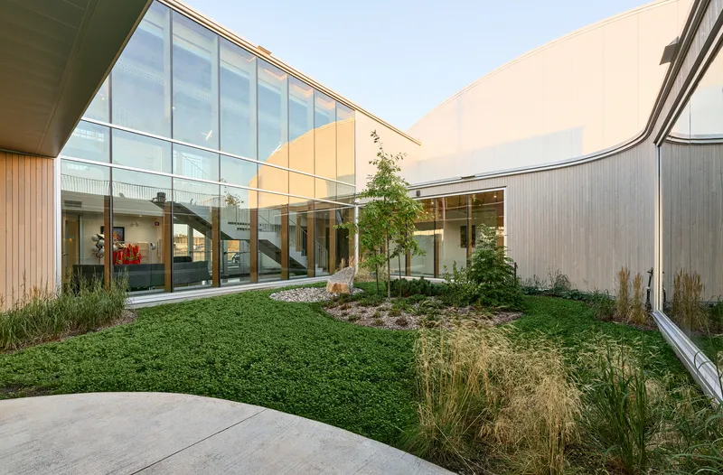 Interior courtyard with planted beds and grasses framed by glazed walls and corrugated metal cladding