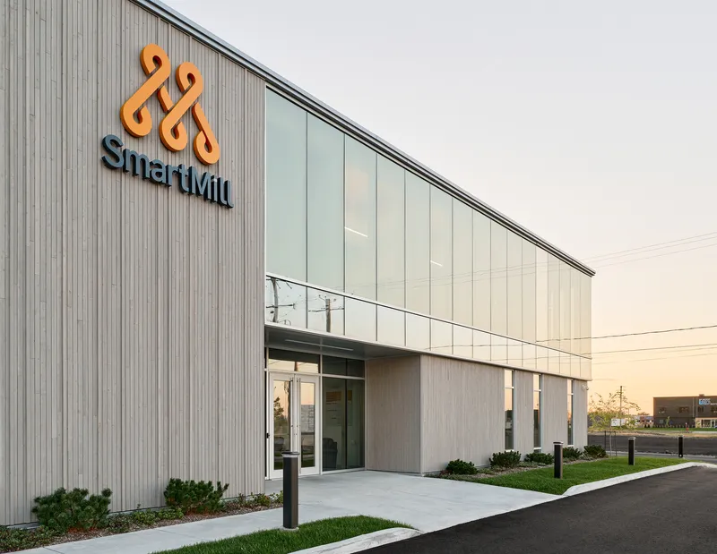 Entrance facade with vertical metal cladding and translucent panel upper story photographed at sunset