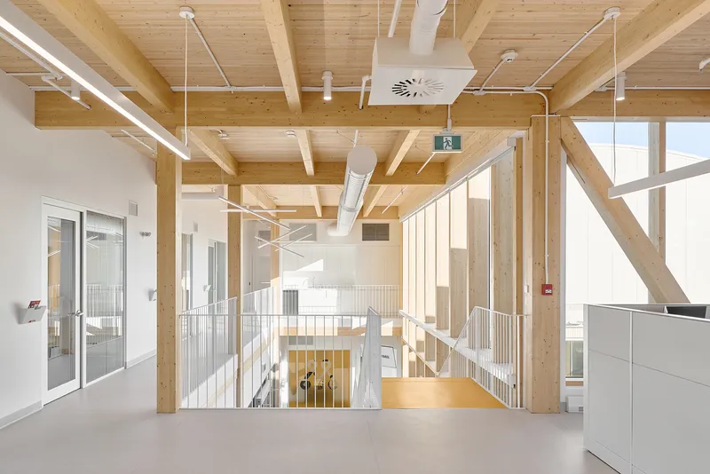 Interior atrium with exposed timber beams and metal railings overlooking a central stairwell