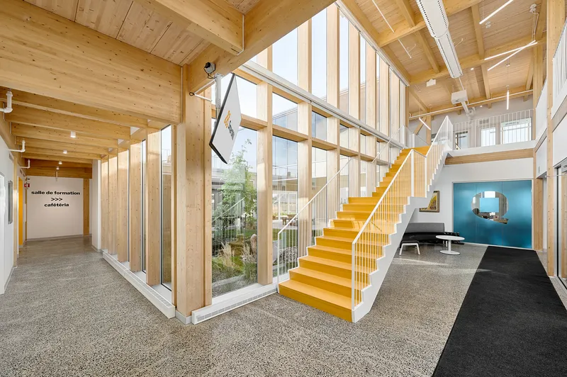 Yellow painted timber staircase ascending through double-height space with courtyard window beyond