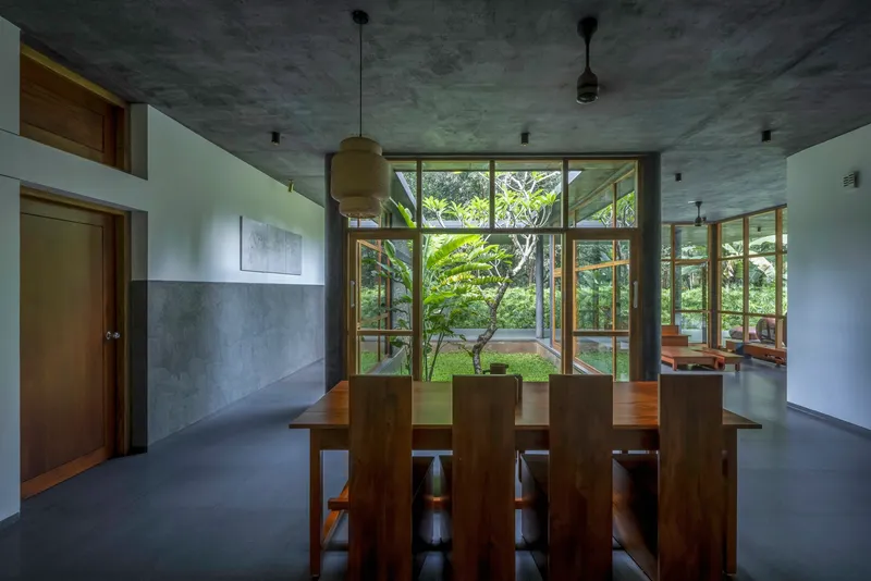 Dining area with timber table and chairs beneath board-formed concrete ceiling and pendant light fixtures