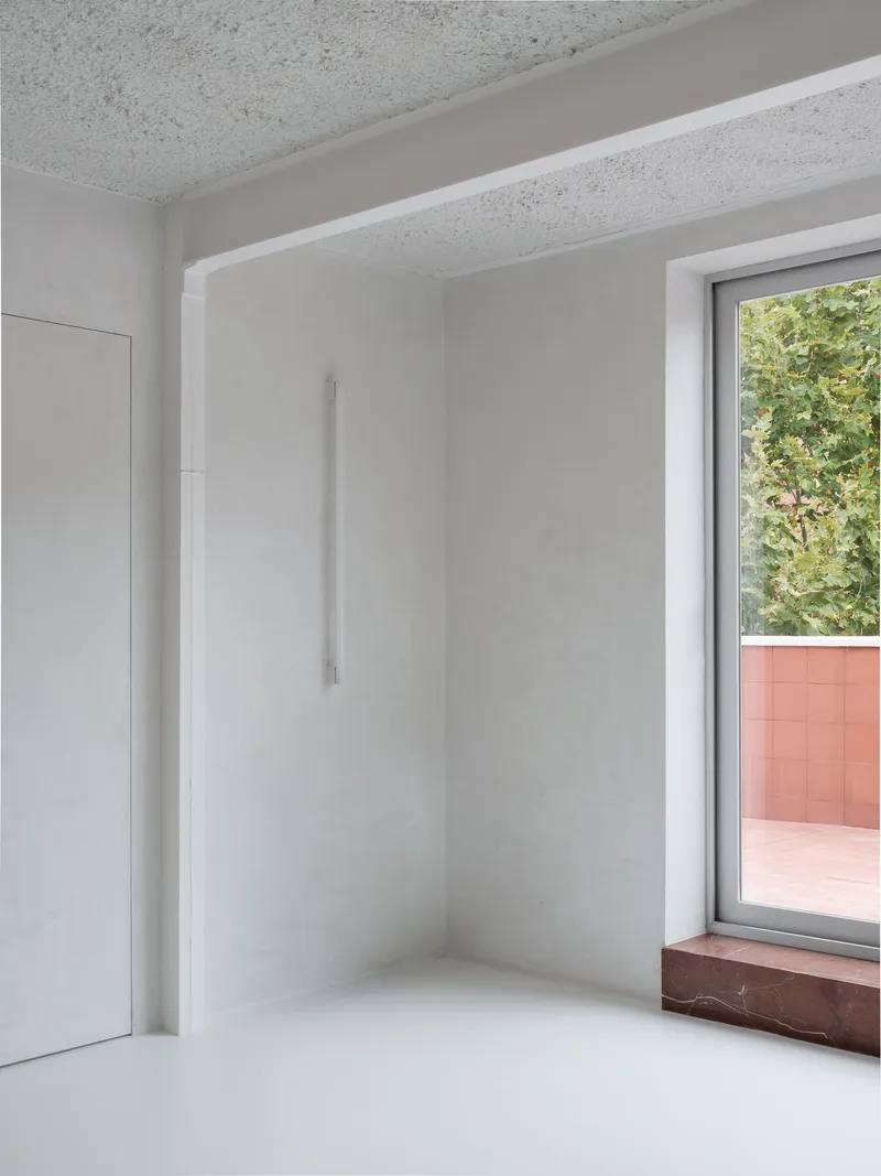 Interior corner with window opening to planted balcony and red marble sill beneath terrazzo ceiling