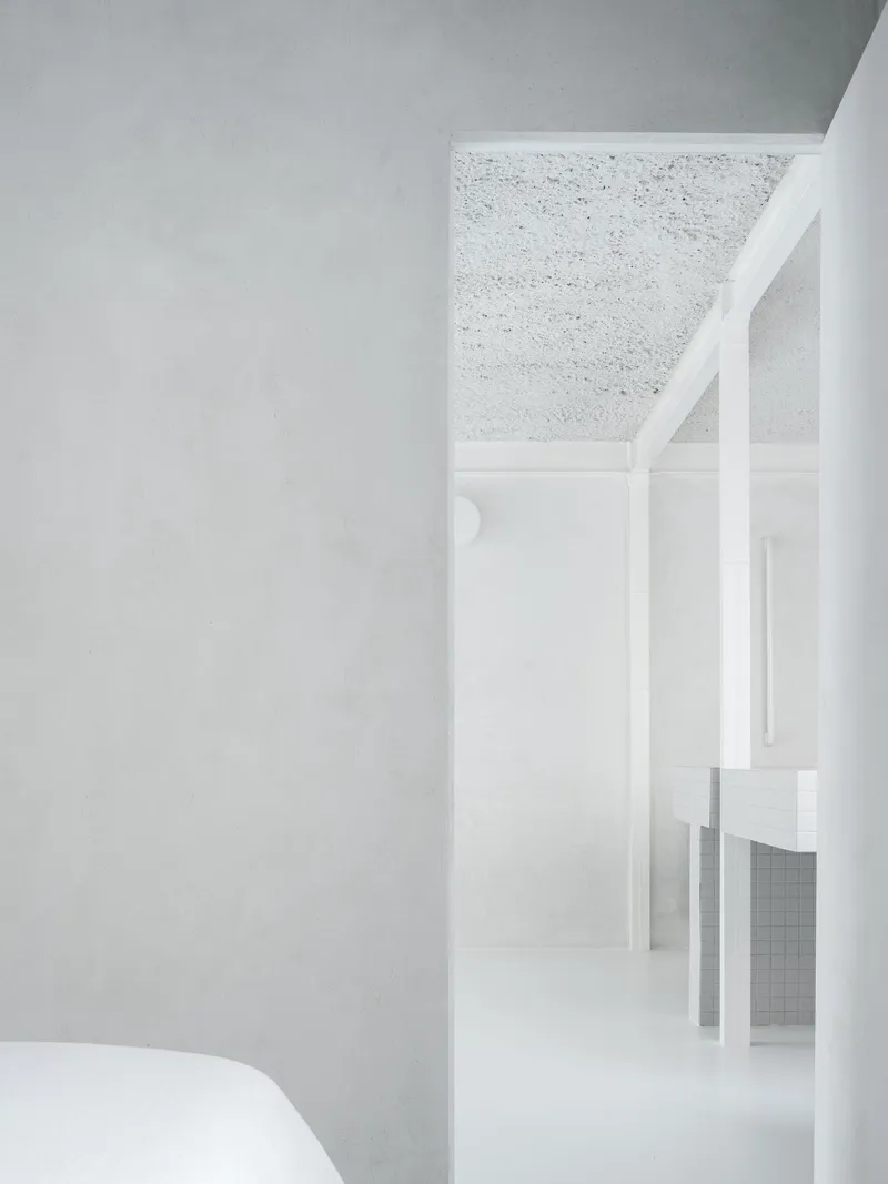 White painted steel frame partition beneath terrazzo ceiling with view through to kitchen beyond