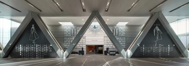 Symmetrical view down a corridor with triangular steel portals framing a polished stone floor