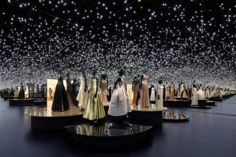 Exhibition gallery with circular display plinths and a field of suspended starlight points overhead