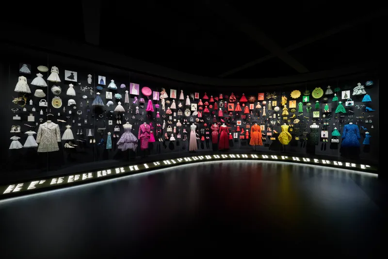 Panoramic display wall showing garments and objects arranged by color gradient from white to blue