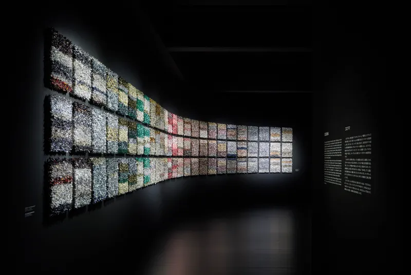 Curved backlit wall composed of gridded image panels transitioning through the color spectrum
