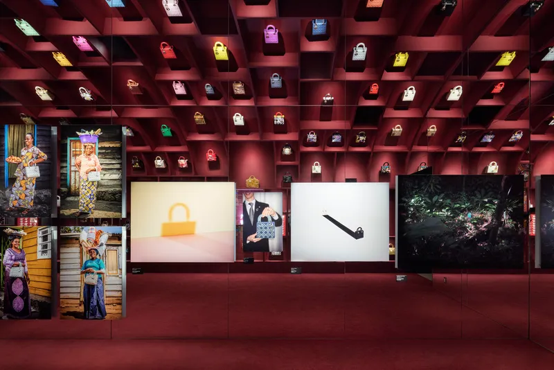 Coffered ceiling grid displaying illuminated handbags above burgundy walls and backlit panels