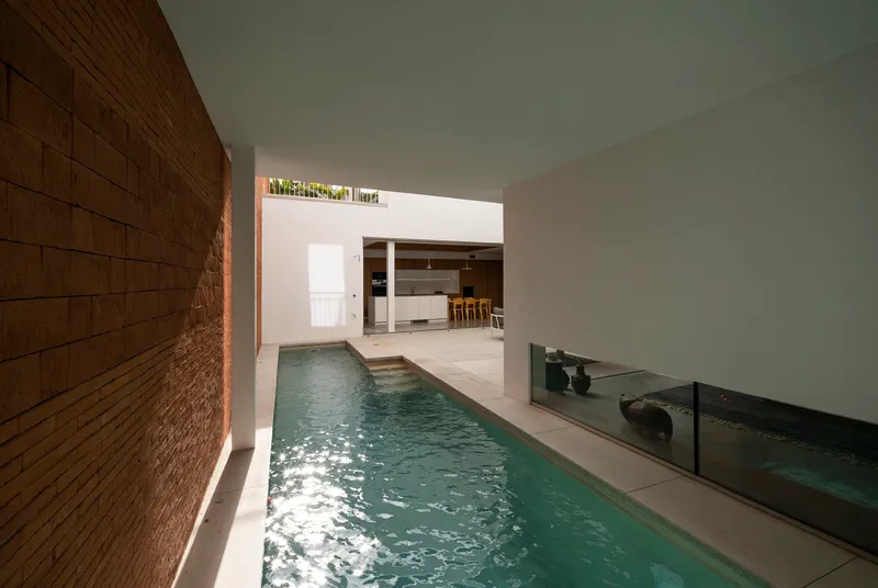 Indoor lap pool with timber cladding on one wall and water reflecting sunlight from above