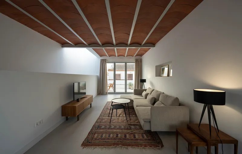 Living room with timber-clad ceiling beams and clerestory window bringing natural light above the sofa