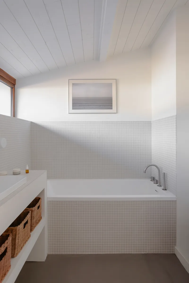 Bathroom with white mosaic tile tub surround, timber window trim and dark grey floor