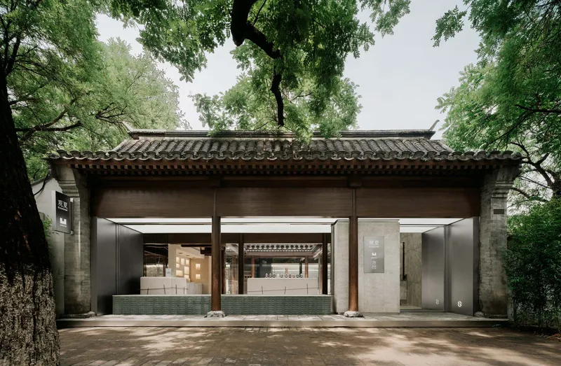 Frontal view of the open pavilion structure showing timber beams beneath curved tile eaves without pedestrians