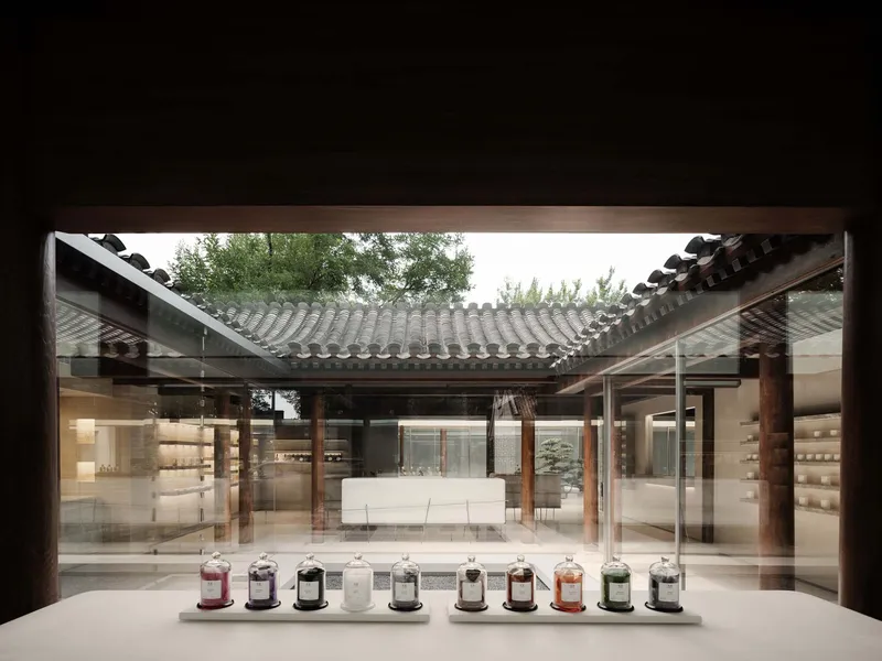 View through a display window toward the interior courtyard with timber columns and row of vessels on the sill