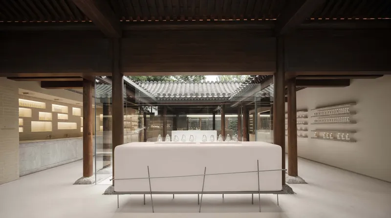 Interior courtyard with white display counter under timber beams framed by glass and tiled roofs beyond