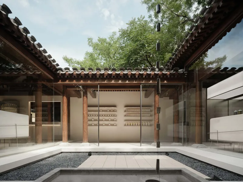 Courtyard with gravel floor and white shelving wall beneath timber eaves and green tree canopy above