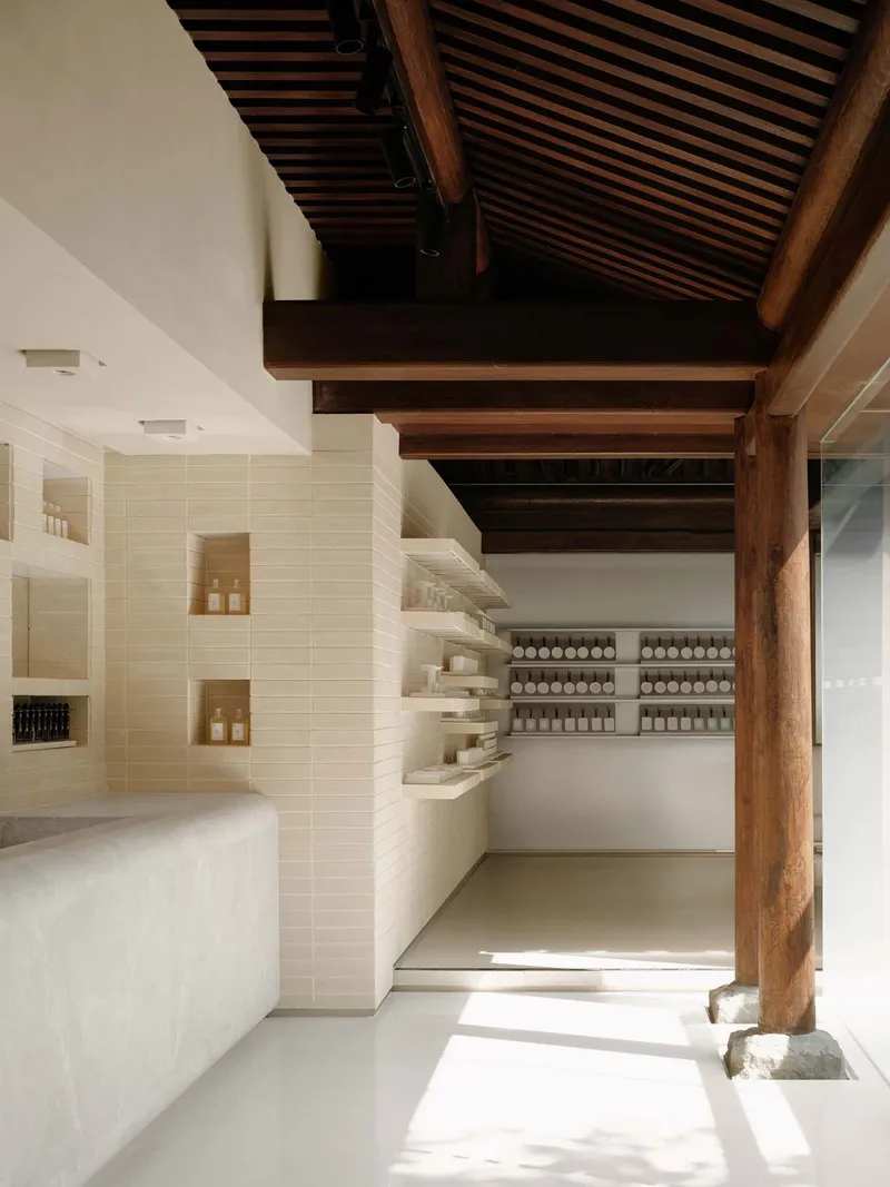 This architectural image showcases a minimalist retail space with a blend of modern and traditional elements. The design features clean lines, white walls, and