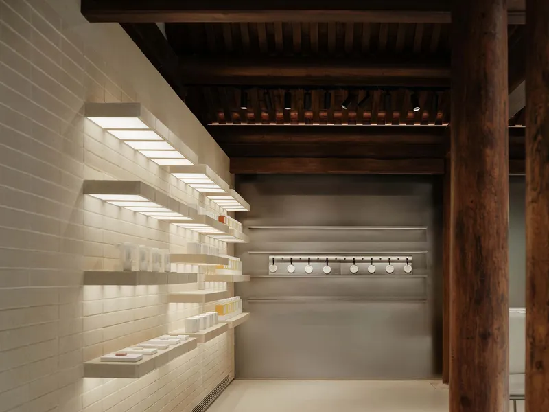 Illuminated product shelves wrapping around timber columns in a retail space with slatted ceiling above