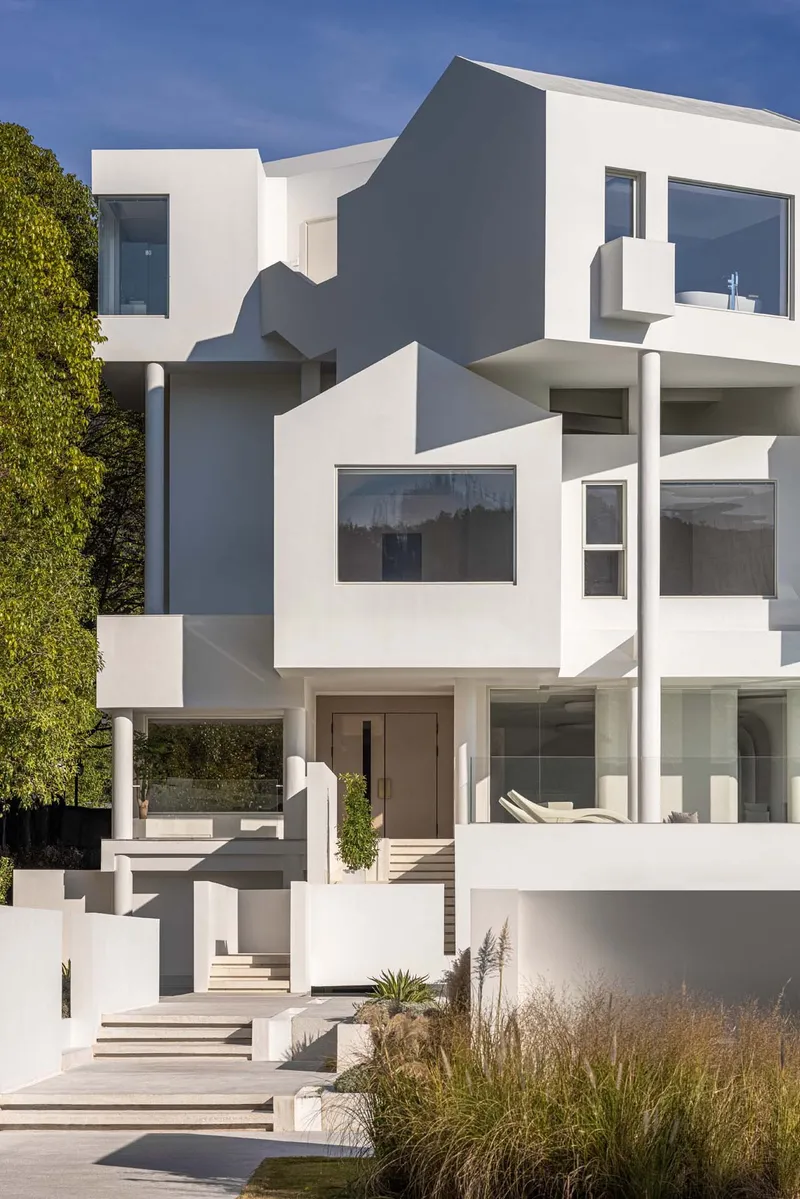 Cascading white terraces with planted beds and curved geometries under bright daylight