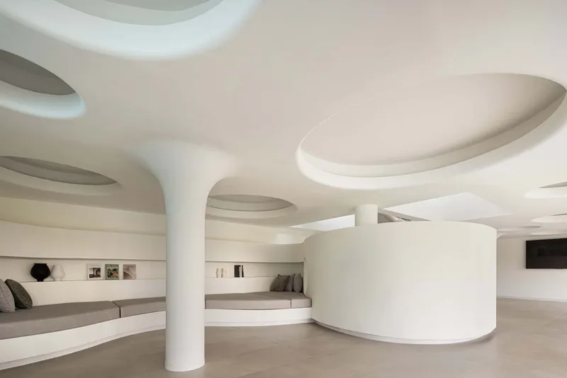 Interior lounge with white columns, curved ceiling cutouts and built-in seating niches
