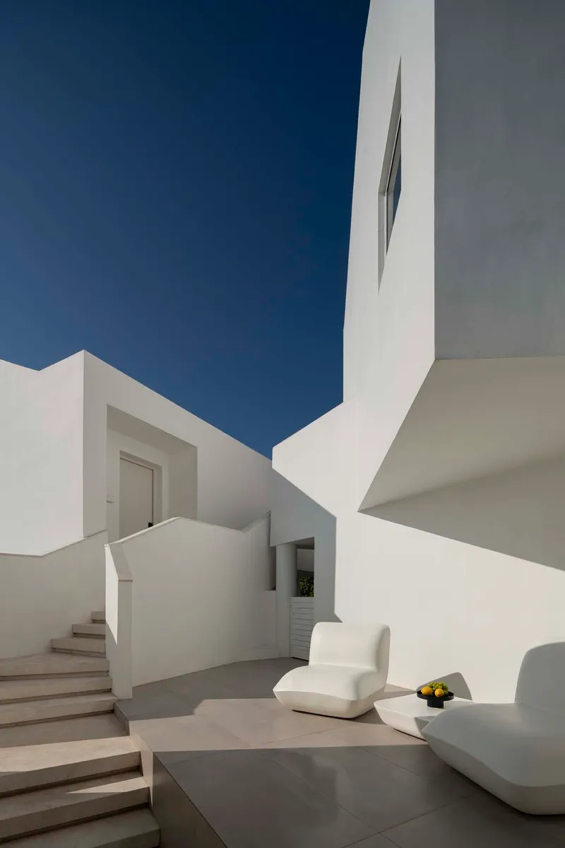 Exterior terrace with white seating and angular walls framing a deep blue sky