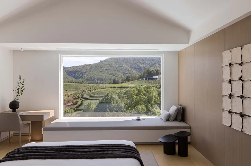 Bedroom with wide horizontal window seat framing terraced vineyard rows and distant hillside