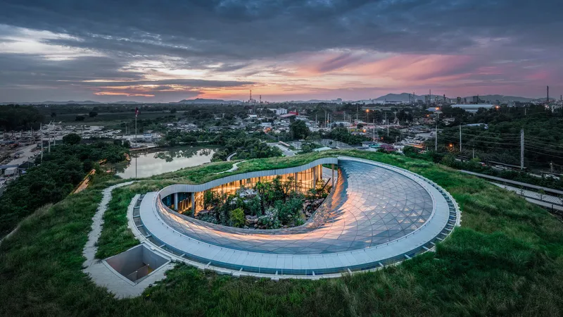 Aerial view of the curving ring-shaped building with green roof and interior courtyard at sunset