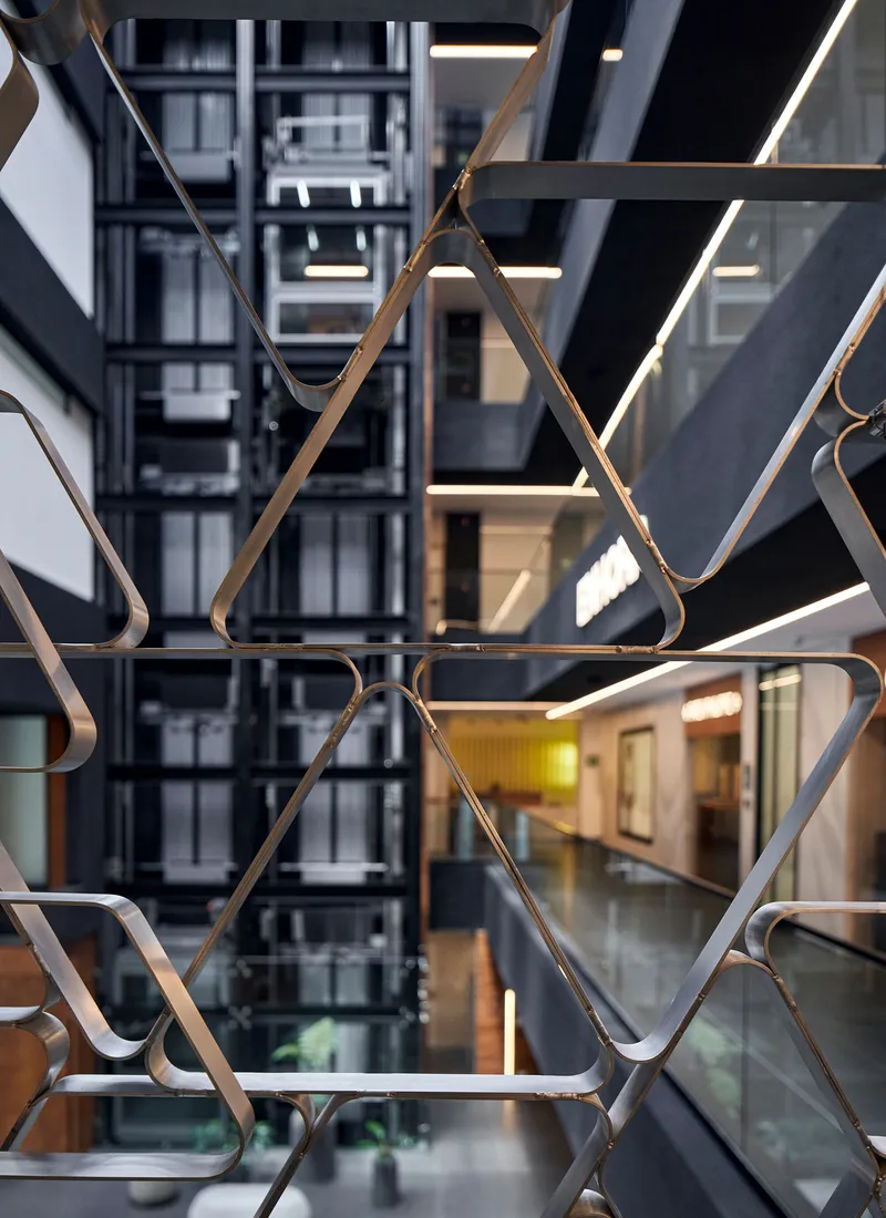 Geometric metal screen with triangular pattern viewed through interior atrium void