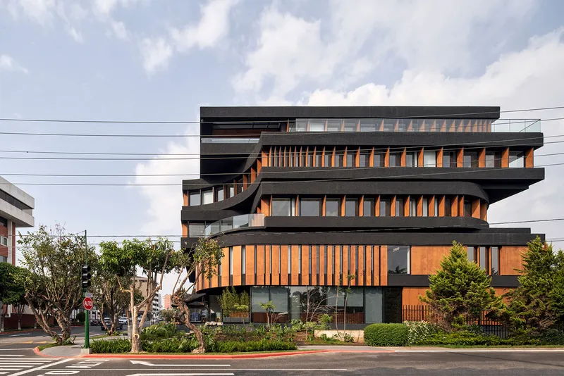 Stacked facade with dark concrete slabs and vertical timber screening viewed from the street under cloudy skies