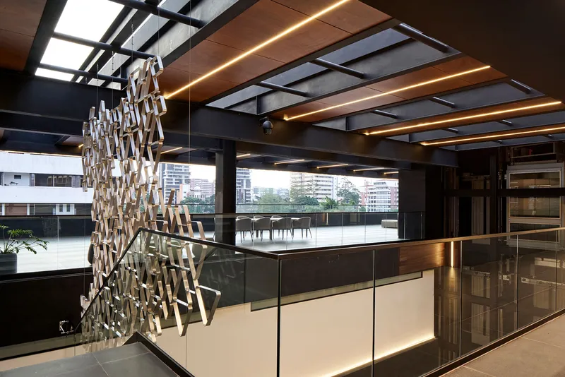 Kitchen island with backlit base below exposed ceiling beams with integrated linear lighting