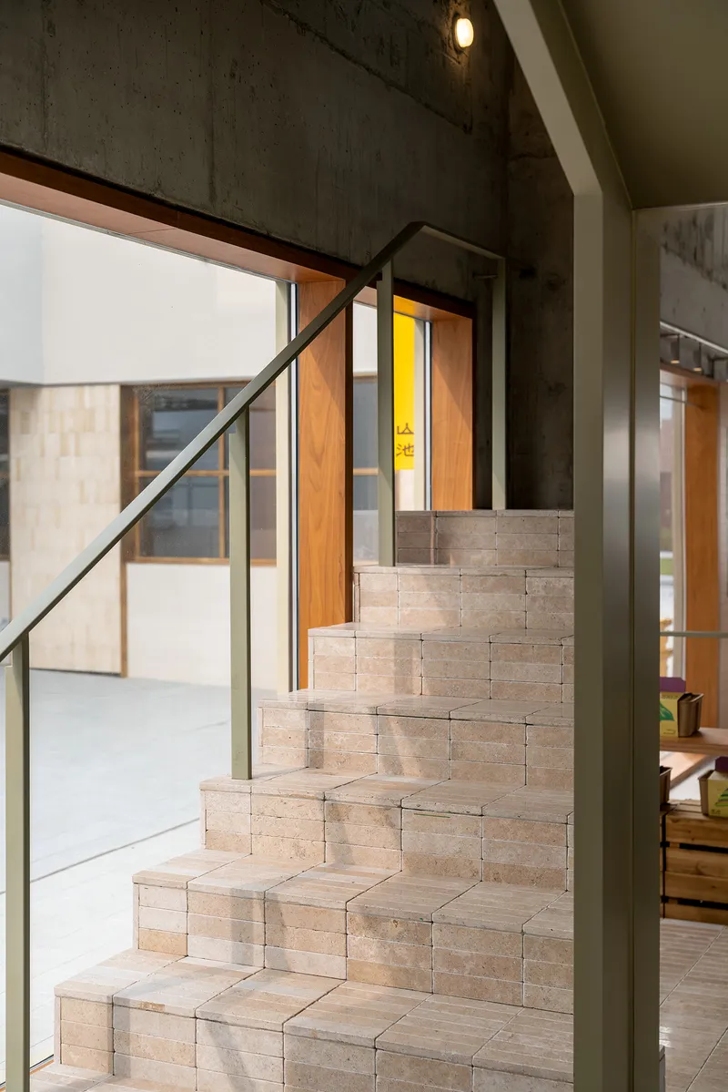 Stacked timber block staircase with steel handrail beside a board-formed concrete wall