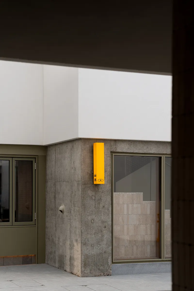 Interior courtyard corner with yellow emergency call box mounted on a cast concrete column at dusk