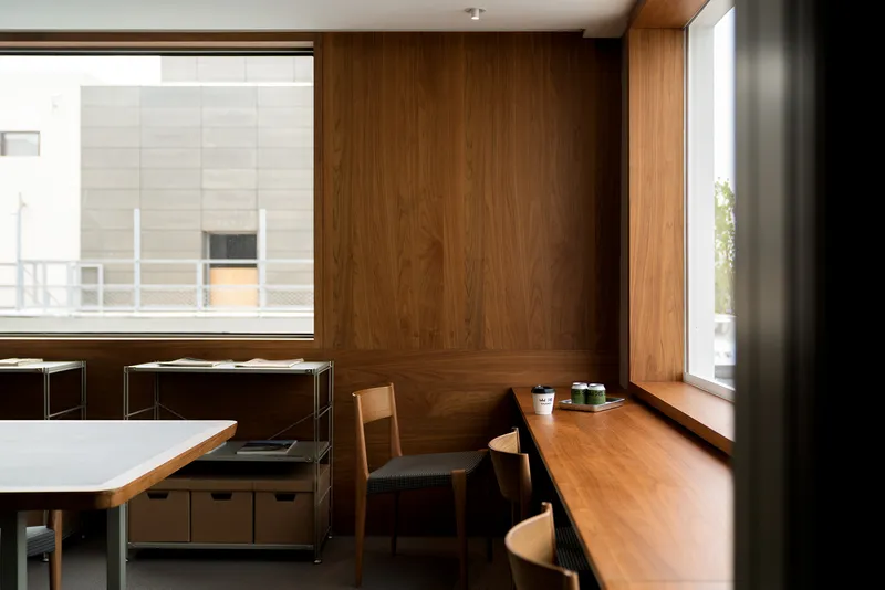 Corner reading nook with timber-paneled walls and built-in seating beneath two tall windows