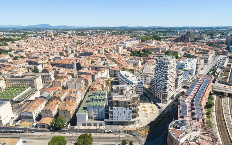 Aerial view of the spiraling tower and surrounding urban blocks beside railway tracks in afternoon light