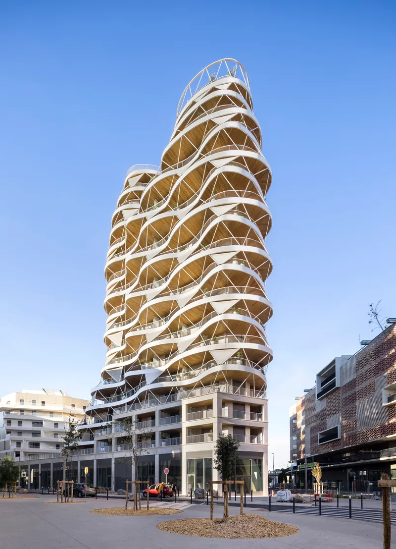 Street view of the tower showing its diagonal structural exoskeleton and stacked terraces under clear sky