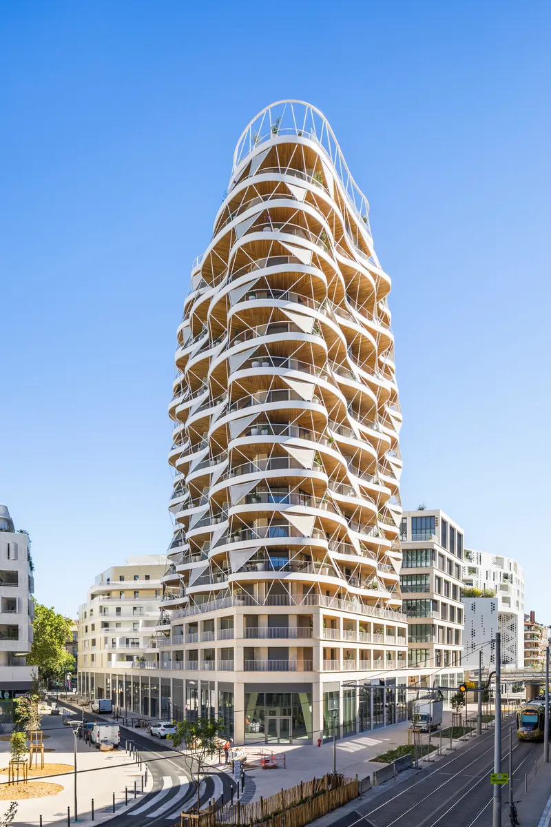 Corner perspective of the spiraling tower with its triangulated facade above a rectangular podium base