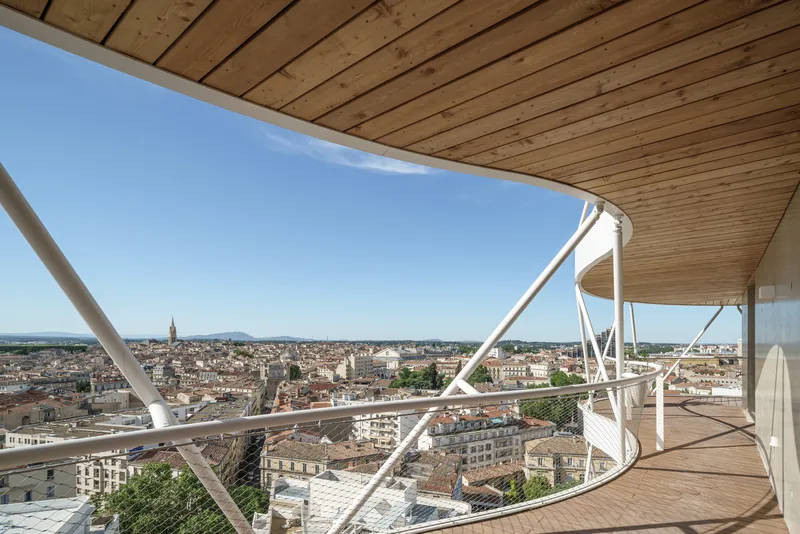 Curved timber soffit and white structural bracing framing the rooftop terrace view across the town