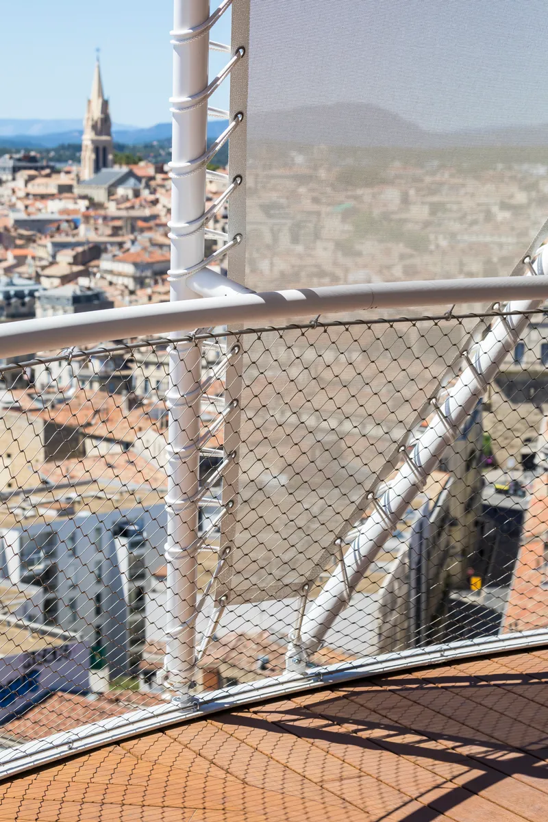 Detail of white steel cables and mesh safety netting on the rooftop deck edge