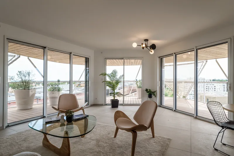 Living room with floor-to-ceiling glazing opening to a rooftop terrace with potted plants and city views