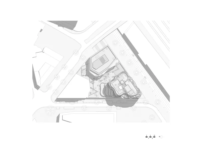 Site plan drawing showing the triangular building and its landscaped surroundings between adjacent streets and parking areas