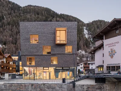 Obermoser + Partner Architekten Wrap an Alpine Tourist Center in Pre-Greyed Larch Shingles