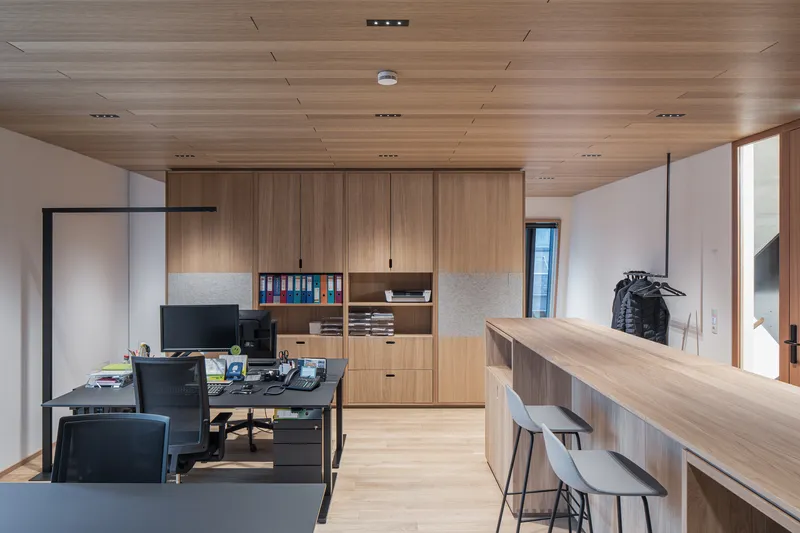 Open office area with timber cabinetry, work desks and wood plank ceiling with recessed lighting