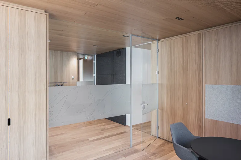 Glass-partitioned meeting room with white marble half-height walls and timber paneling throughout
