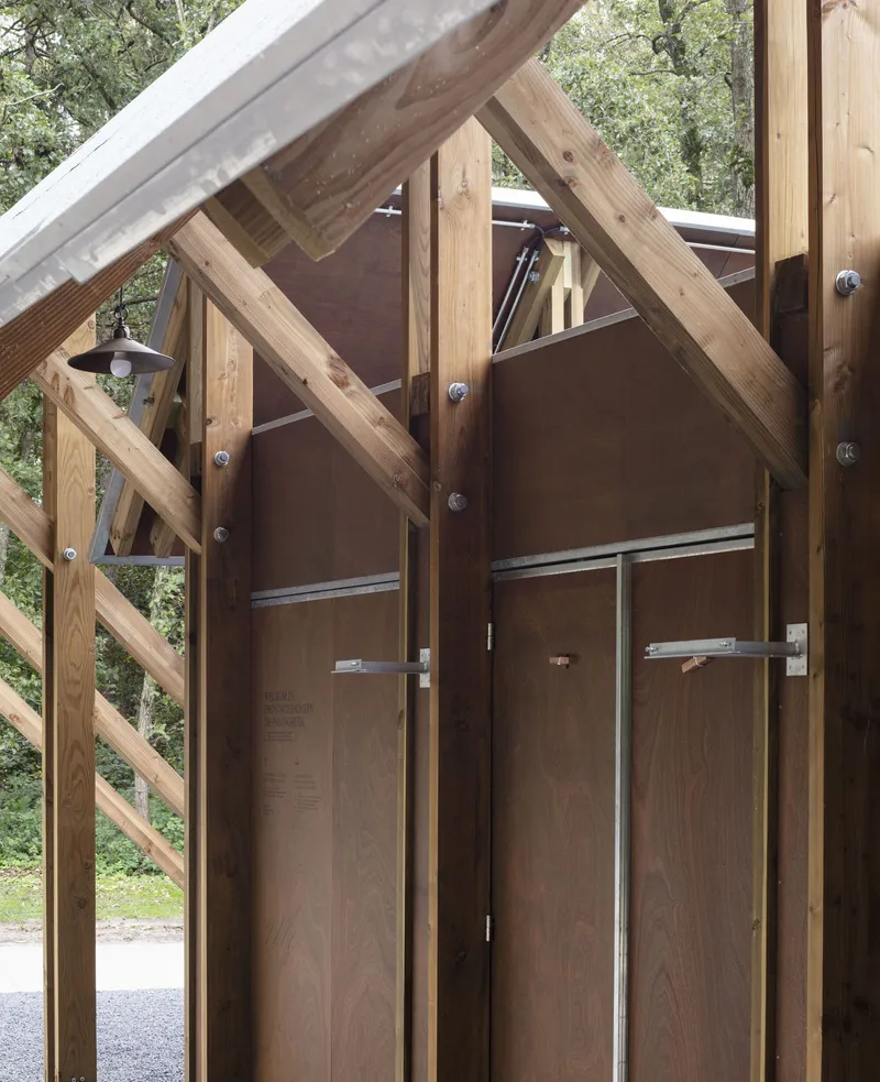Entrance with timber-framed gabled portal and bolted timber columns framing dark wood panel doors