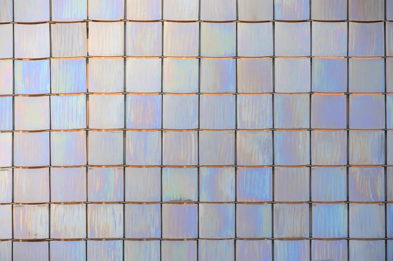 Detail of rectangular glass tiles with visible metallic frames and soft iridescent surfaces
