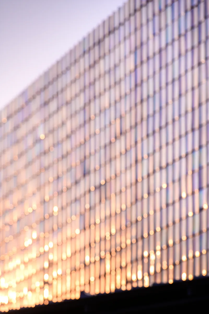 Vertical slat facade with interior lighting glowing through at dusk