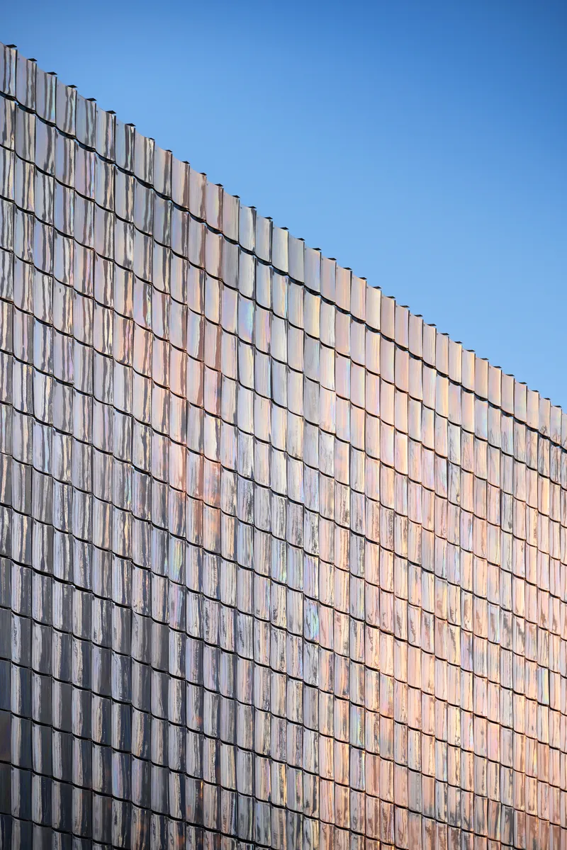 Angled view of the glass tile curtain wall showing diagonal shadow lines in daylight