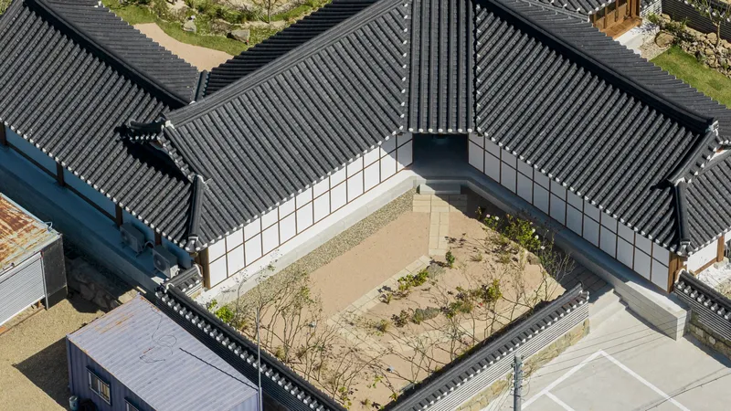Aerial view of the tiled roofs enclosing a gravel courtyard with young trees and plantings
