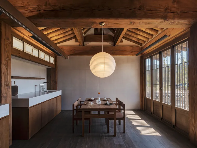 Dining area with exposed timber ceiling beams and paper lantern illuminated by afternoon sunlight