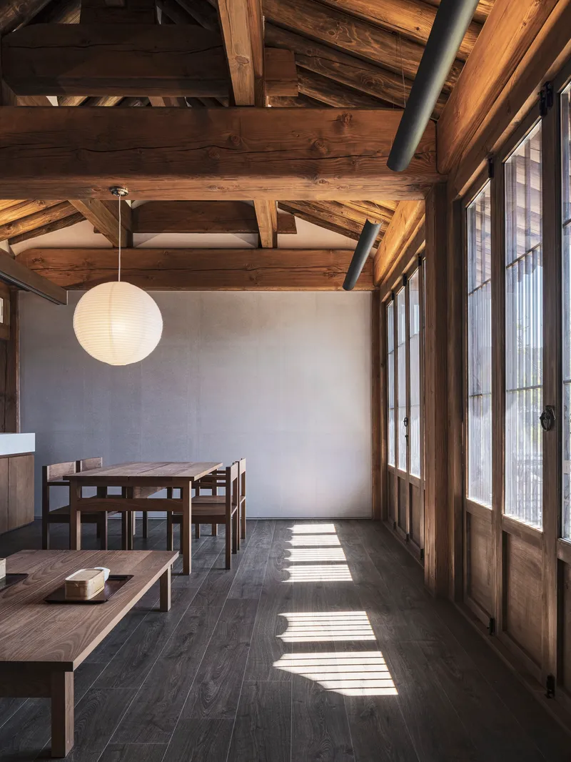 Sunlight casting grid shadows across dark timber floors through paper panel doors